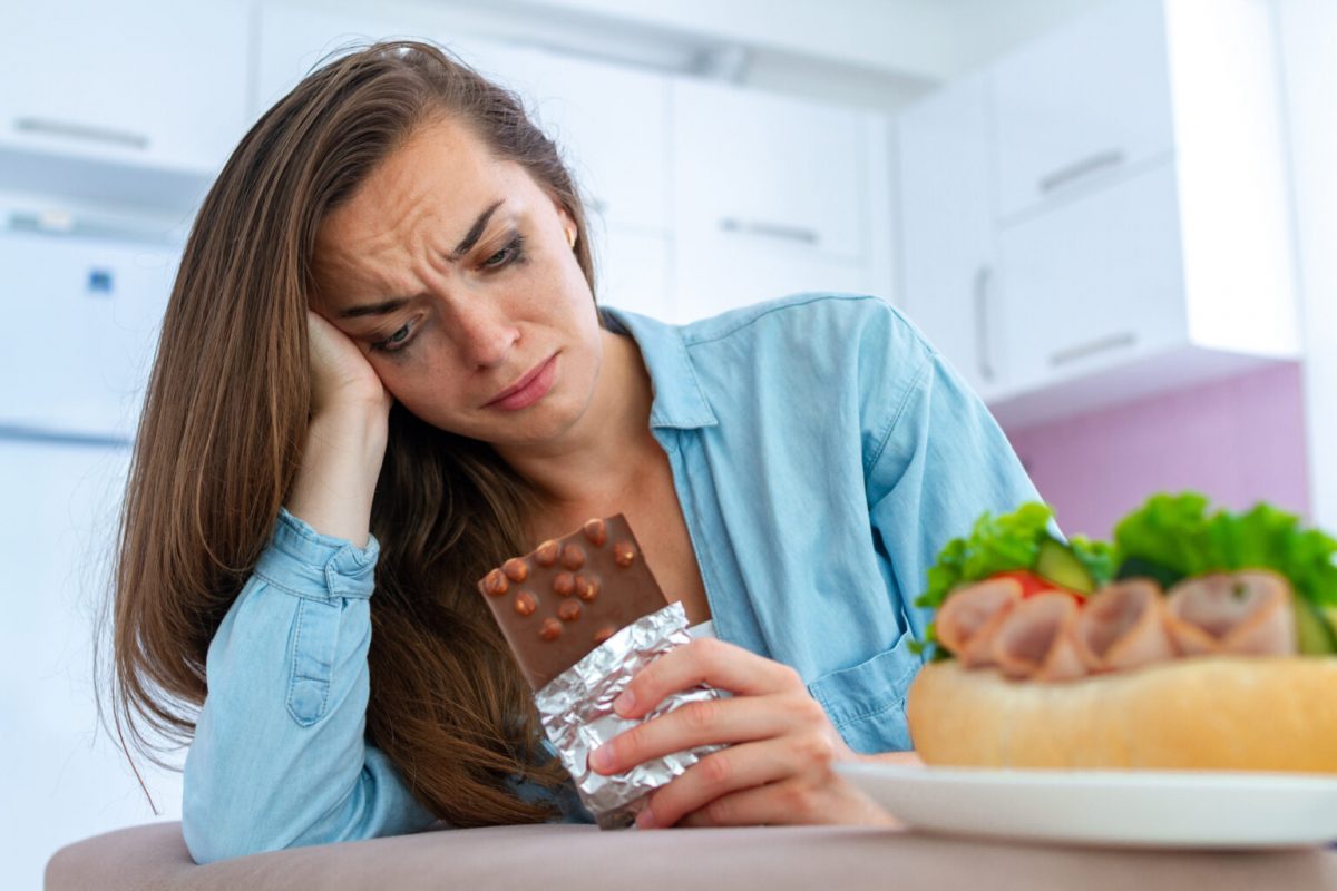 Сумна жінка їсть шоколад через депресію та емоційний стрес