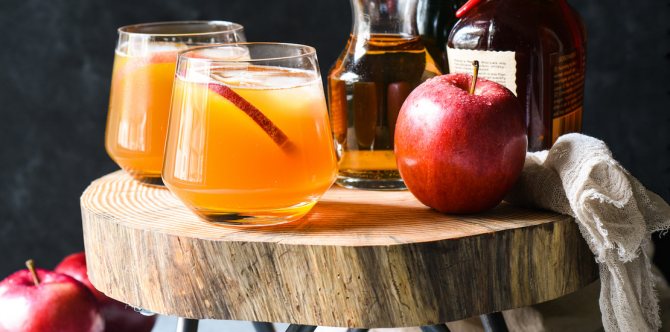 пляшки і склянки з сидром, поруч яблуко