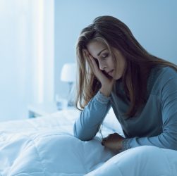 Женщина в депрессии не спит ночью, прикасается ко лбу и страдает от бессонницы