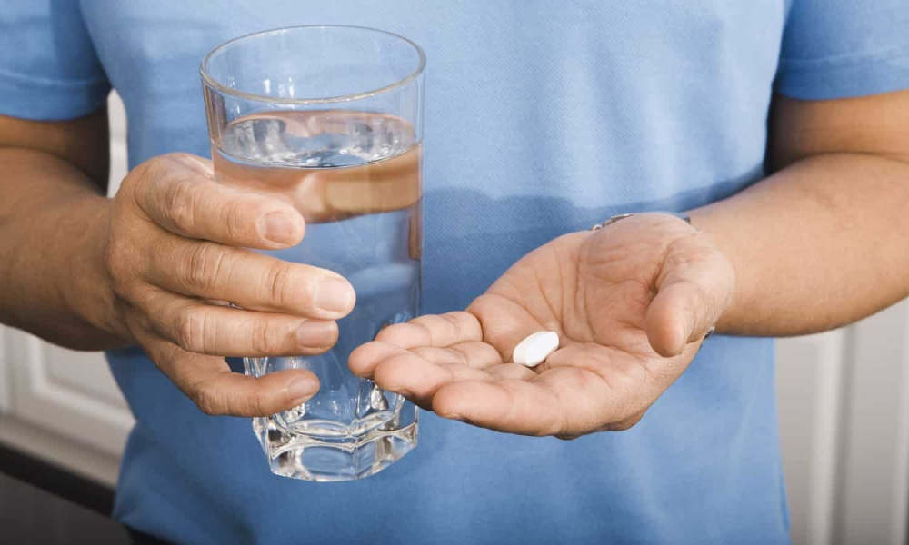 Людина приймає таблетки з водою