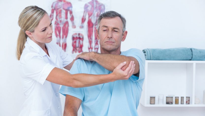 Доктор розтягує руку людини в медичному кабінеті